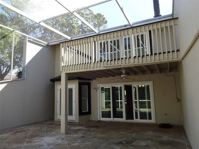 rear view of property with a patio, a balcony, ceiling fan, and glass enclosure