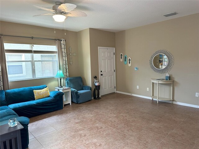 living room featuring ceiling fan, a textured ceiling, and light tile patterned flooring