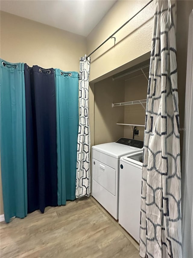 laundry area with independent washer and dryer and light hardwood / wood-style flooring