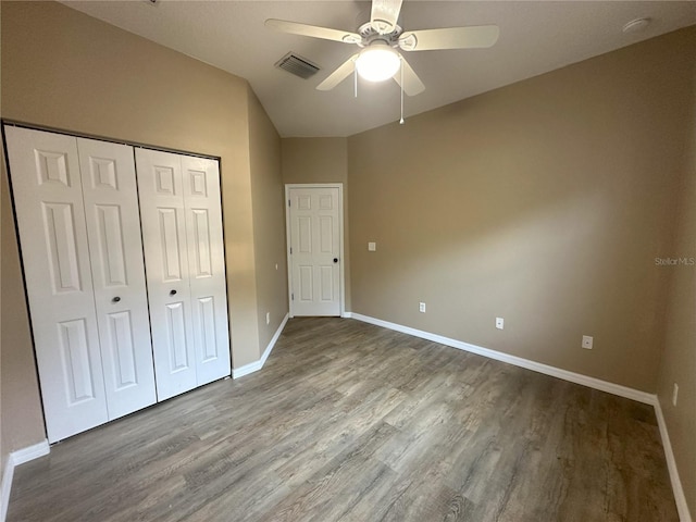 unfurnished bedroom featuring a closet, ceiling fan, wood-type flooring, and vaulted ceiling