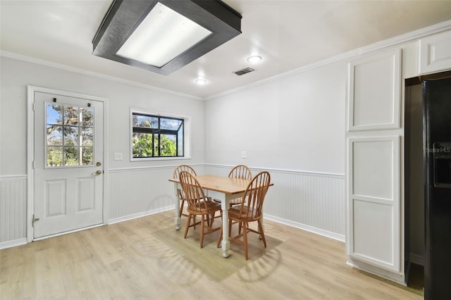 dining area with ornamental molding and light wood-type flooring