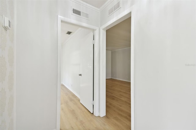 hallway with light hardwood / wood-style floors and crown molding