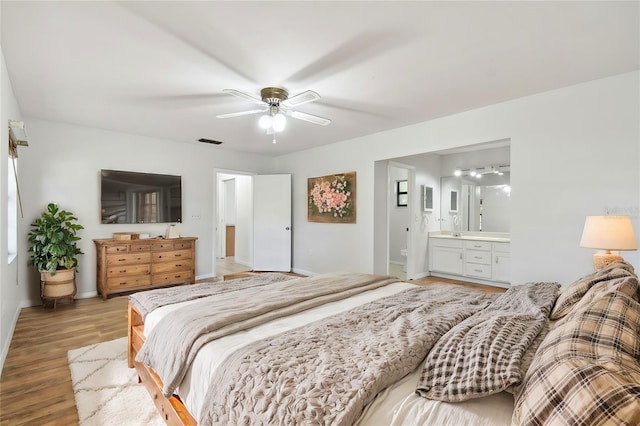 bedroom with ceiling fan, ensuite bathroom, and hardwood / wood-style floors