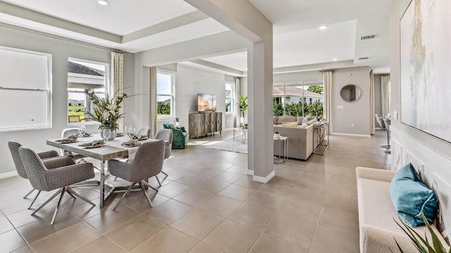 dining space featuring light tile patterned flooring and a tray ceiling