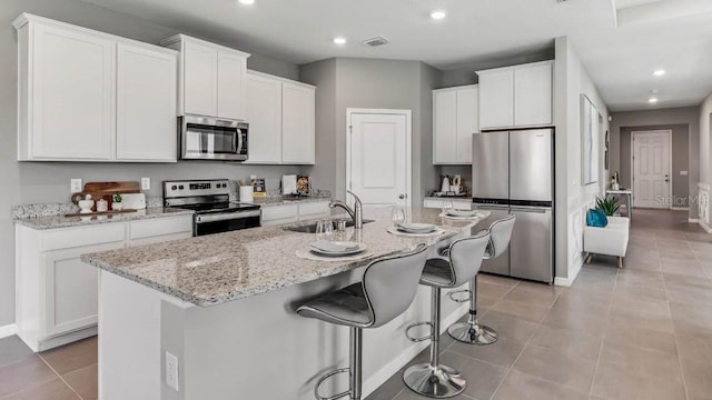 kitchen featuring white cabinetry, stainless steel appliances, and an island with sink