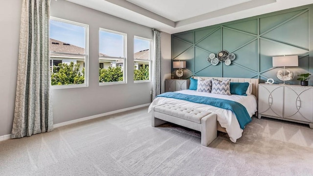 bedroom with light carpet and a raised ceiling