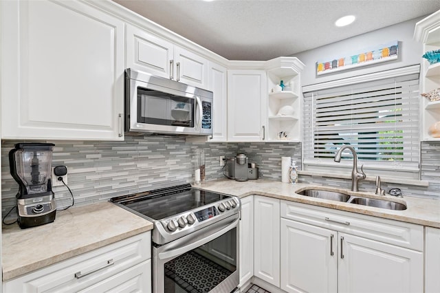 kitchen with stainless steel appliances, backsplash, sink, white cabinets, and a textured ceiling