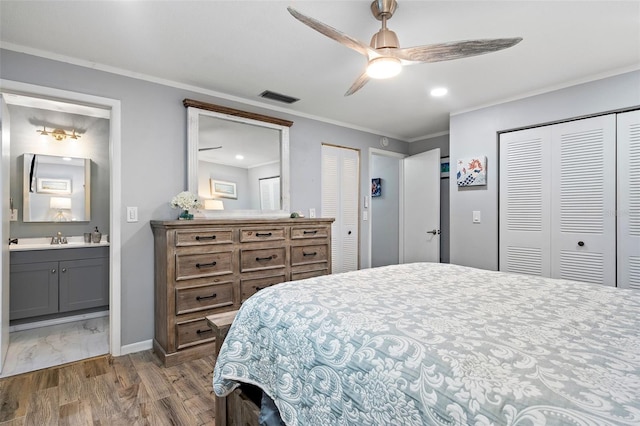 bedroom featuring two closets, ceiling fan, dark hardwood / wood-style flooring, ensuite bath, and sink