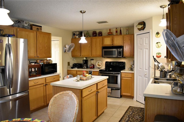 kitchen featuring pendant lighting, a center island, stainless steel appliances, and a textured ceiling