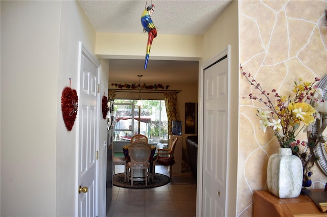 hall with tile patterned floors and a textured ceiling