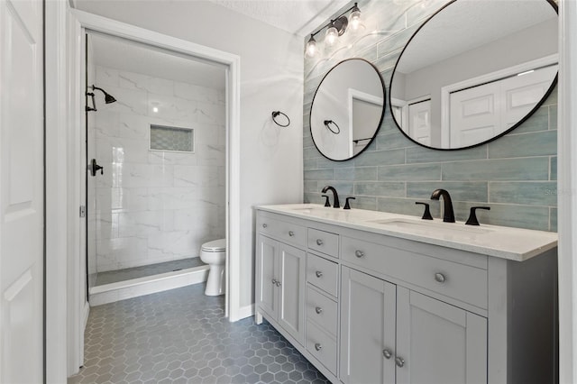 bathroom with tiled shower, tile patterned floors, vanity, and toilet