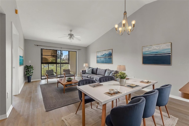 dining space featuring lofted ceiling, ceiling fan with notable chandelier, and light wood-type flooring