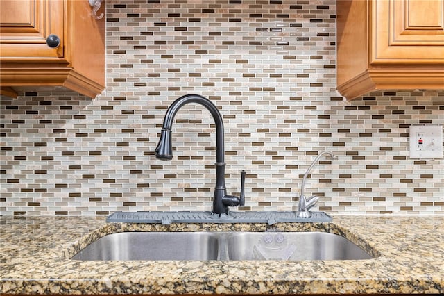 kitchen with backsplash, sink, and light stone counters