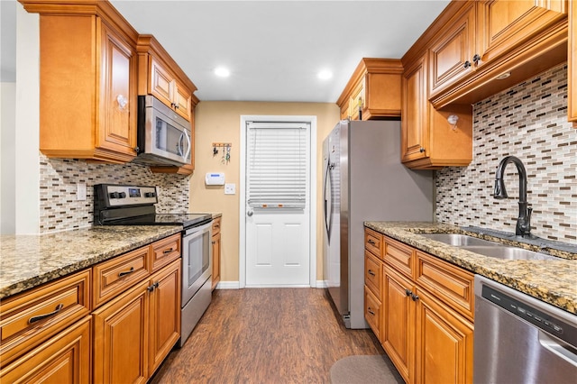 5621 Moog Rd, New Port Richey, FL 34652 - kitchen featuring stainless steel appliances, a sink, dark wood finished floors, backsplash, and brown cabinetry