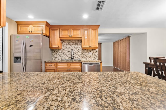 kitchen with sink, decorative backsplash, light stone counters, and stainless steel appliances