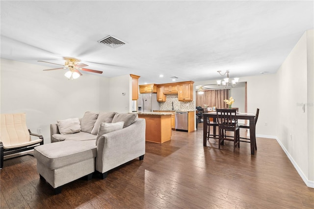 living room featuring dark wood-type flooring, sink, and ceiling fan with notable chandelier
