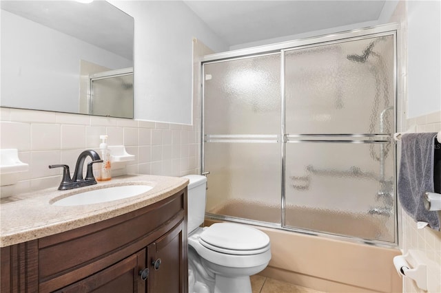 5621 Moog Rd, New Port Richey, FL 34652 - full bathroom featuring tile walls, toilet, vanity, combined bath / shower with glass door, and wainscoting
