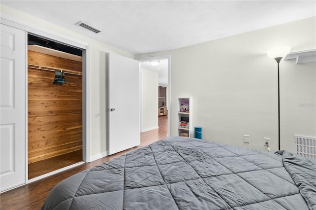 bedroom with hardwood / wood-style flooring, a closet, and wood walls