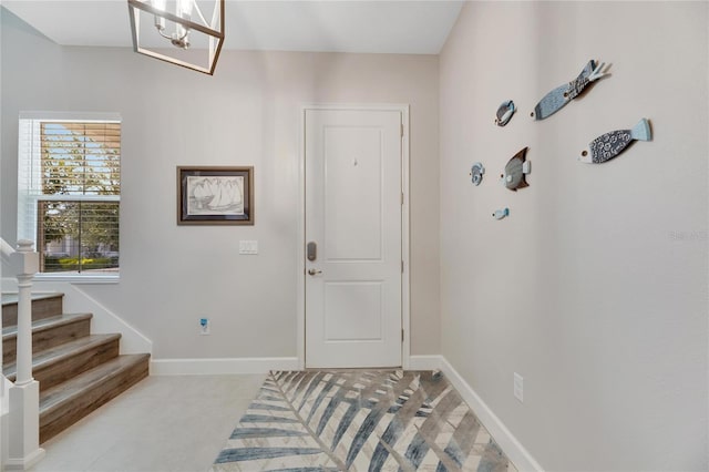 foyer featuring an inviting chandelier, baseboards, and stairway
