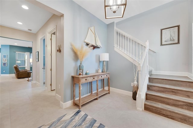 stairs with tile patterned floors and a notable chandelier