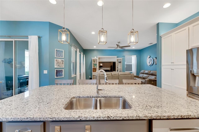 kitchen with sink, ceiling fan, decorative light fixtures, and a center island with sink