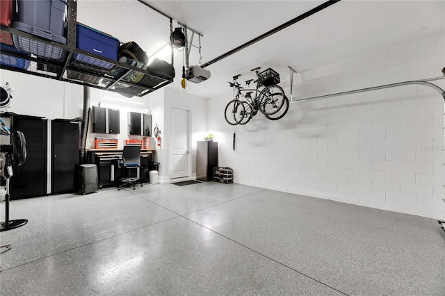 garage featuring concrete block wall and a garage door opener