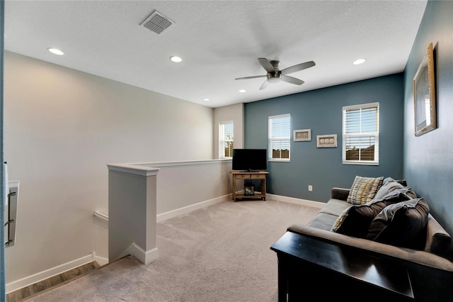 living room featuring ceiling fan, a textured ceiling, and light colored carpet