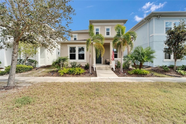 view of front of property with covered porch, a front lawn, and stucco siding