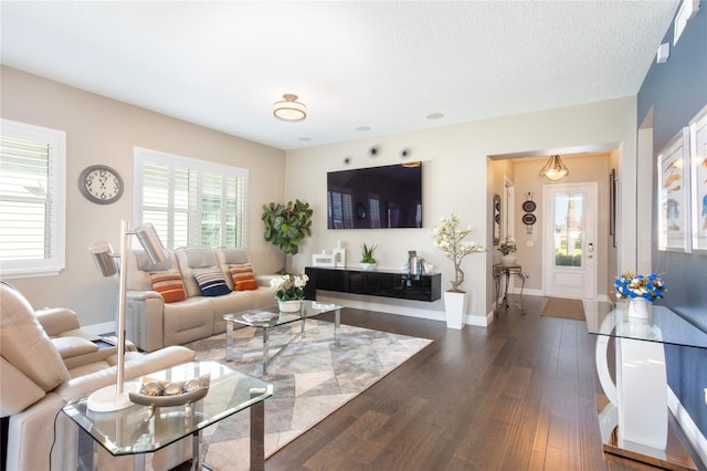 living room with a textured ceiling and dark wood-type flooring