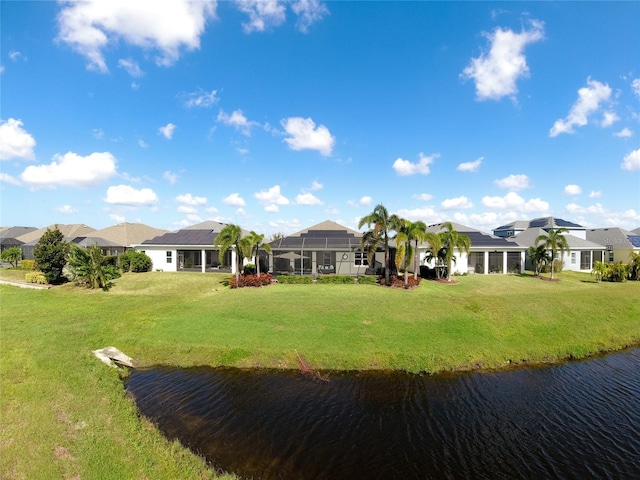 rear view of house featuring a yard, a water view, and a lanai