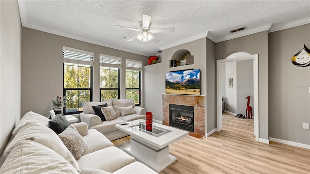 2717 Via Cipriani Unit 622B, Clearwater, FL 33764 - living area featuring ceiling fan, light wood-style floors, a textured ceiling, a tile fireplace, and ornamental molding