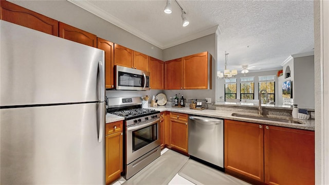 kitchen featuring appliances with stainless steel finishes, a textured ceiling, light stone countertops, crown molding, and sink