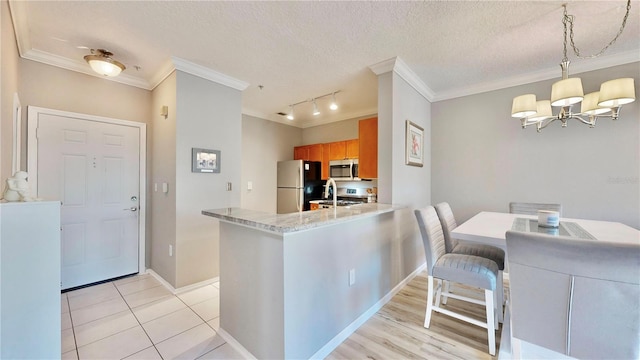 kitchen with a textured ceiling, light stone countertops, a chandelier, crown molding, and stainless steel appliances