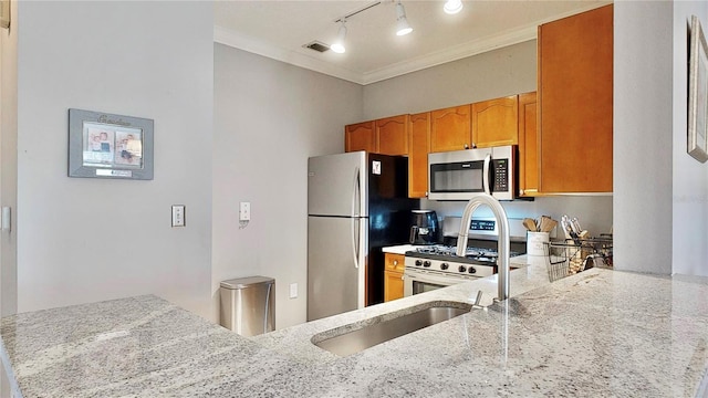 2717 Via Cipriani Unit 622B, Clearwater, FL 33764 - kitchen featuring stainless steel appliances, light stone countertops, track lighting, crown molding, and brown cabinetry
