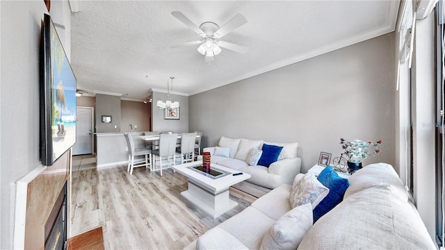 living room featuring ornamental molding, light hardwood / wood-style flooring, a textured ceiling, and ceiling fan with notable chandelier