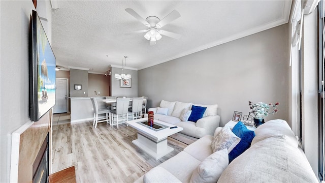 2717 Via Cipriani Unit 622B, Clearwater, FL 33764 - living area featuring ornamental molding, light wood-style flooring, a ceiling fan, a chandelier, and a textured ceiling