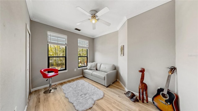 sitting room with ornamental molding, light wood-type flooring, and ceiling fan