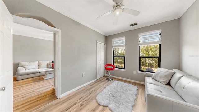 sitting room featuring ceiling fan, crown molding, and light wood-type flooring