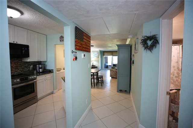 1901 Oyster Catcher Ln Unit 814, Clearwater, FL 33762 - kitchen featuring white cabinets, tasteful backsplash, stainless steel electric range oven, black microwave, and light tile patterned floors