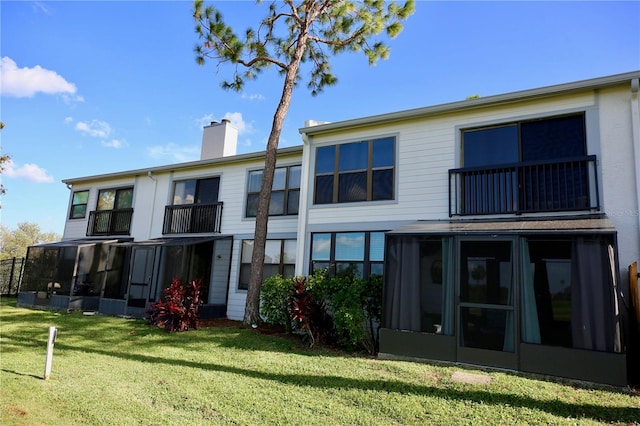 back of property featuring a sunroom and a lawn