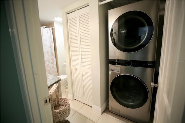 laundry area featuring light tile patterned floors and stacked washing maching and dryer