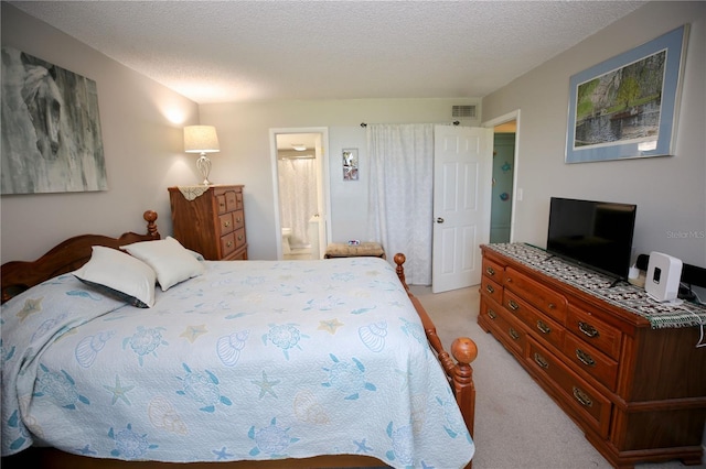 bedroom featuring connected bathroom, light carpet, and a textured ceiling