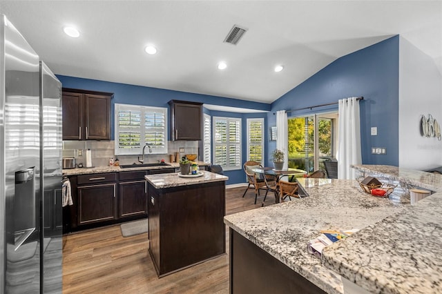 kitchen featuring light hardwood / wood-style flooring, a center island, plenty of natural light, and stainless steel fridge with ice dispenser