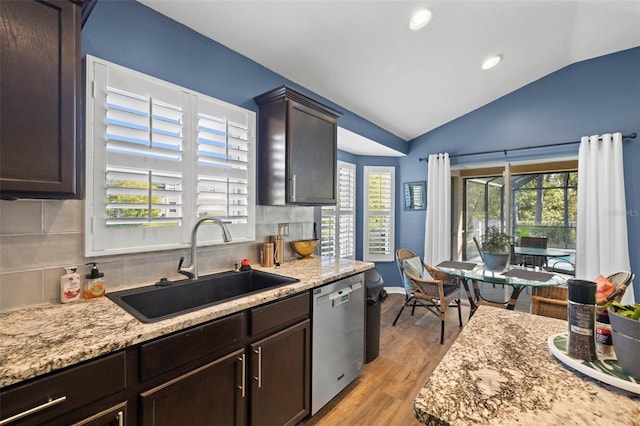 kitchen featuring sink, dishwasher, light hardwood / wood-style floors, vaulted ceiling, and decorative backsplash