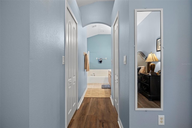 hallway featuring hardwood / wood-style flooring and vaulted ceiling