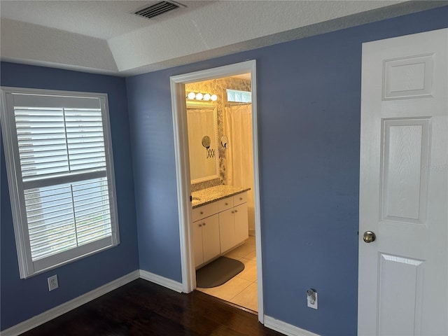 unfurnished bedroom with connected bathroom, dark hardwood / wood-style floors, and a textured ceiling