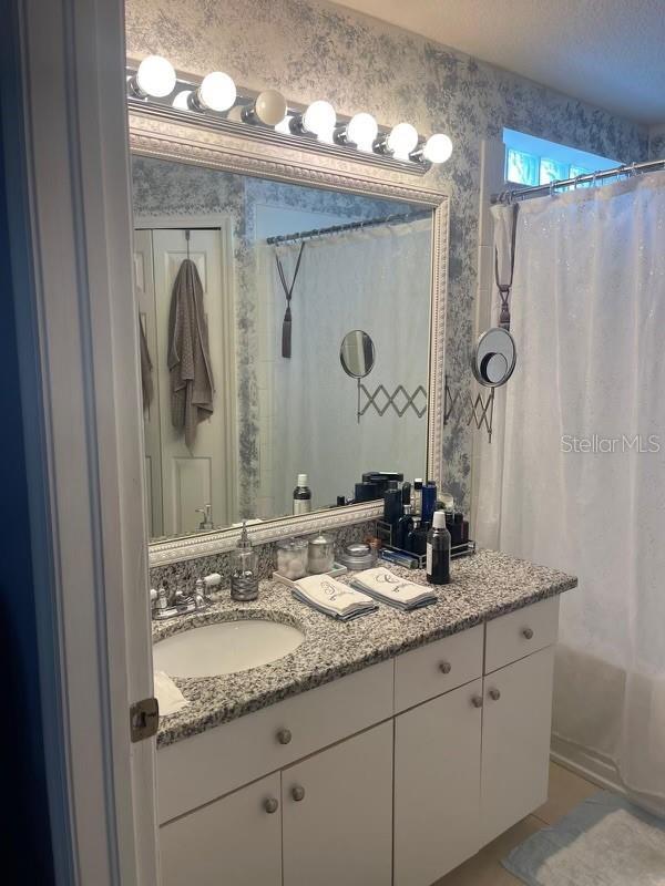 bathroom with vanity, tile patterned floors, shower / tub combo with curtain, and a textured ceiling