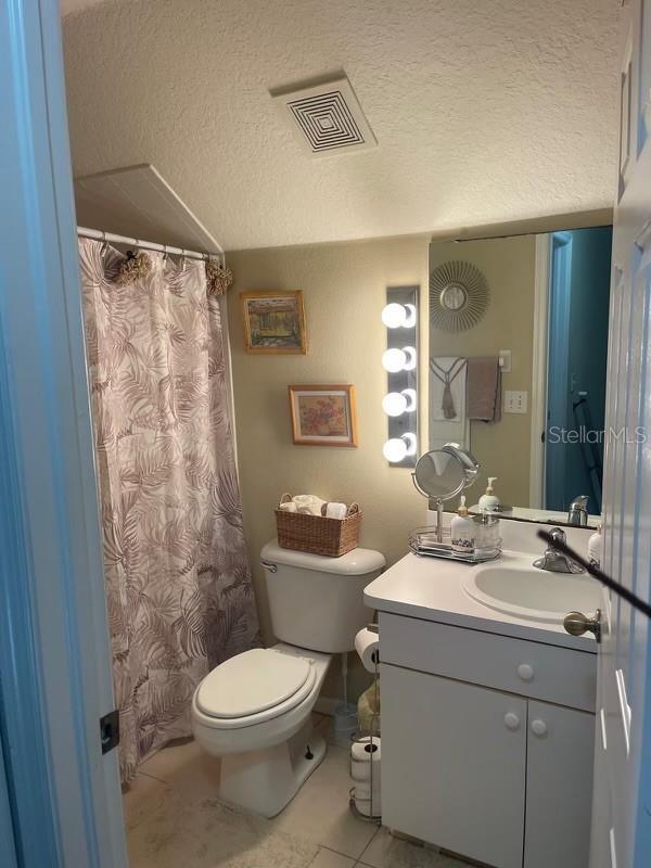 bathroom featuring vanity, tile patterned flooring, toilet, and a textured ceiling