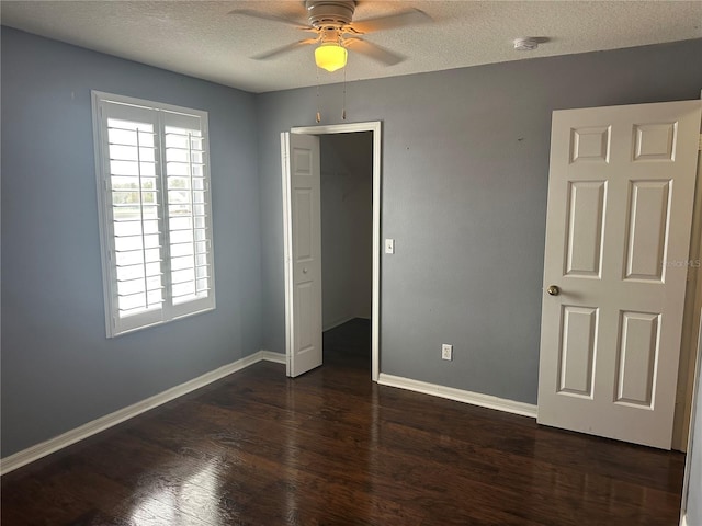 unfurnished bedroom with ceiling fan, a textured ceiling, dark hardwood / wood-style flooring, and a closet