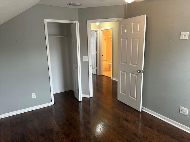 unfurnished bedroom featuring a closet, vaulted ceiling, and dark hardwood / wood-style floors